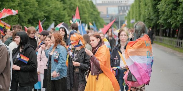 Diverse crowd marching with pride flags in a street parade.